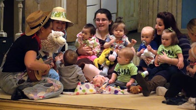 Teacher Marcia Wolf, of the UW-Stout Child and Family Study Center, plays the guitalele as Old McDonald while teaching artist Kris Winter uses a sheep puppet to act out “Old MacDonald had a Farm.” 