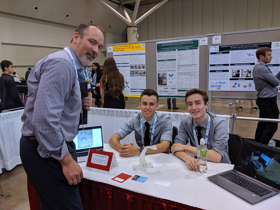 UW-Stout students Kyle Cleven, at left seated, and Michael Laffin attended a conference in Toronto where they presented on ATOM.