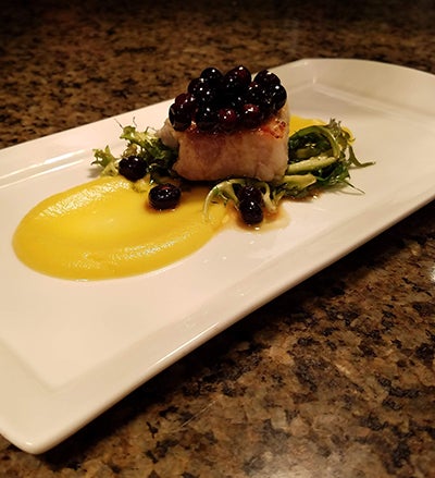 An entrée prepared by Halverson includes pork belly with frisee, acorn squash puree and marinated huckleberries.