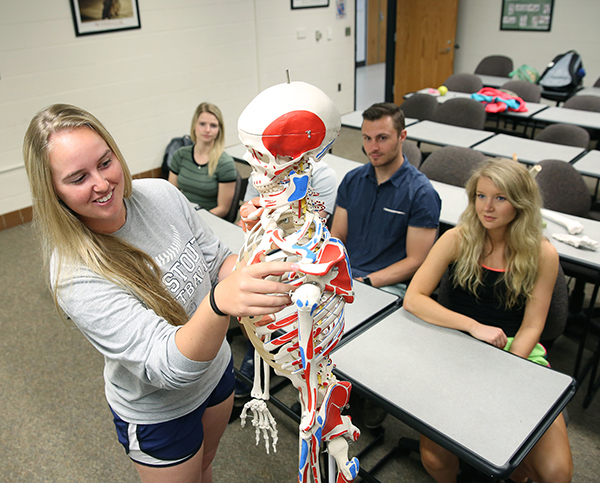 Students work with a skeleton model in a health, wellness and fitness class.