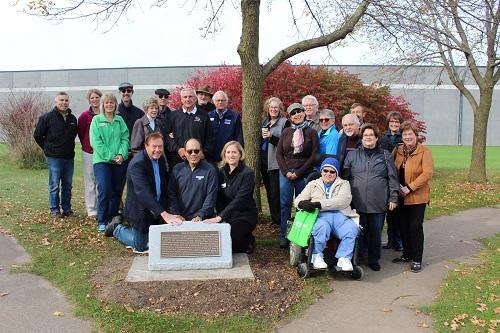 Image of a group of people standing next to the memorial plaque for Paul Hoffman