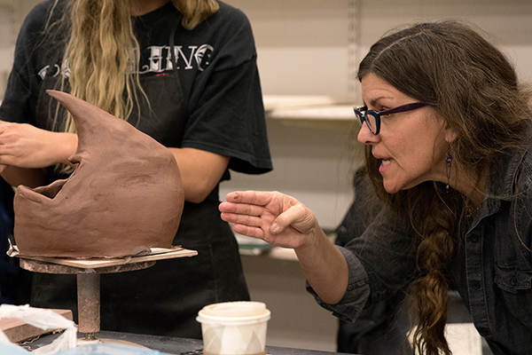 UW-Stout Professor Kate Maury works with students in a ceramics lab.