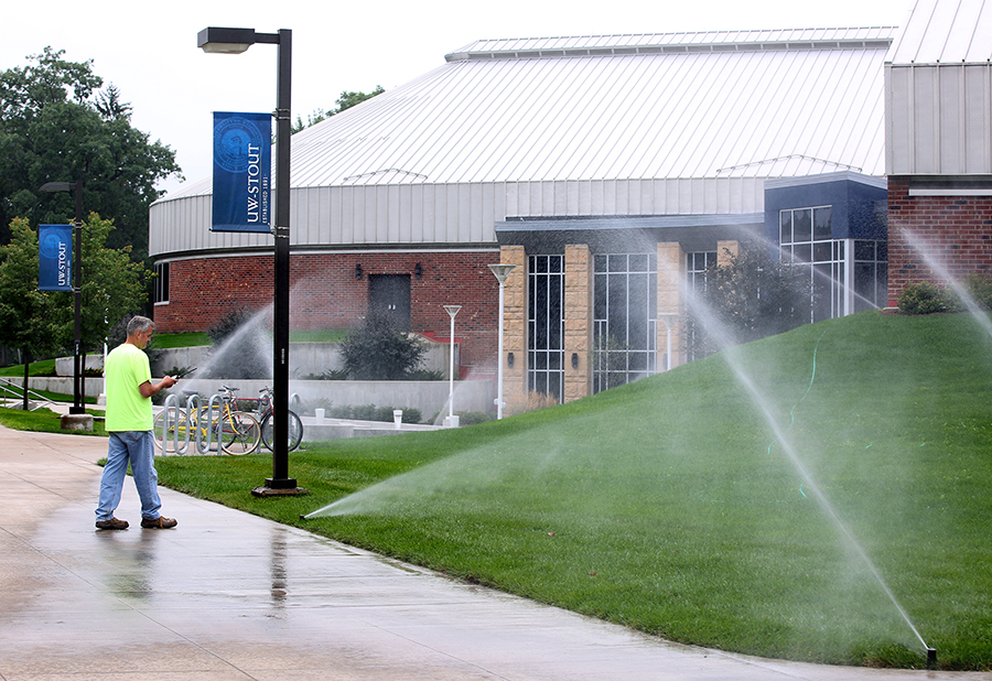 Grounds supervisor Mike Smith, who recently became a nationally certified grounds manager, works on a sprinkler system near UW-Stout’s student center.