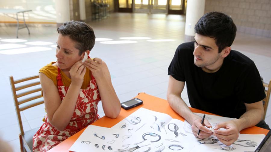 UW-Stout Associate Professor Jennifer Astwood, left, and visiting Russian scholar Azamat Tavitov try a prototype of a sensory safety device that would fit over a person’s ear.
