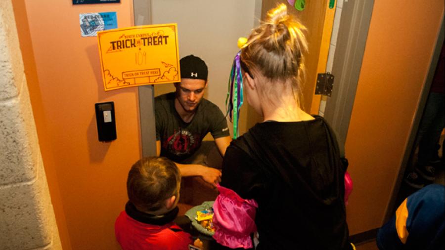 A UW-Stout student hands out candy to children at Red Cedar Hall during the 2016 trick-or-treat event on north campus.