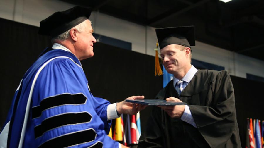 Melvin Winberg receives his diploma Dec. 16 from Chancellor Bob Meyer during commencement at UW-Stout. Winberg spent parts of 17 years working toward his degree. 