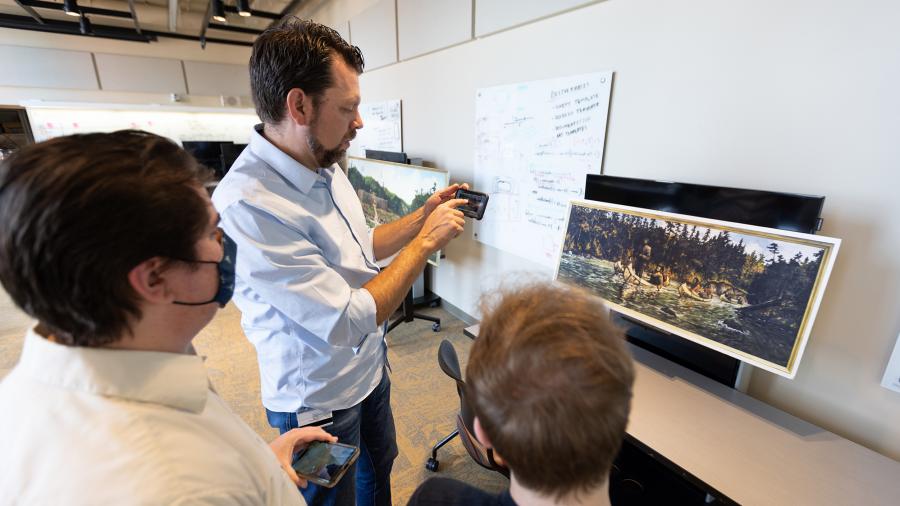 Mitch Ogden, second from left, gives feedback on the SMARTArt app to students Jacob Karr and Brian Bauch. The student-designed app was funded by the Menard Center for the Study of Institutions and Innovation.