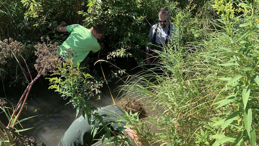 UW-Stout Associate Professor Keith Gilland, right, instructs two high school students as they measure Gilbert Creek during a water volume test.