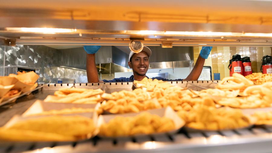 A student worker serves hot food at the Blue Devil Market.