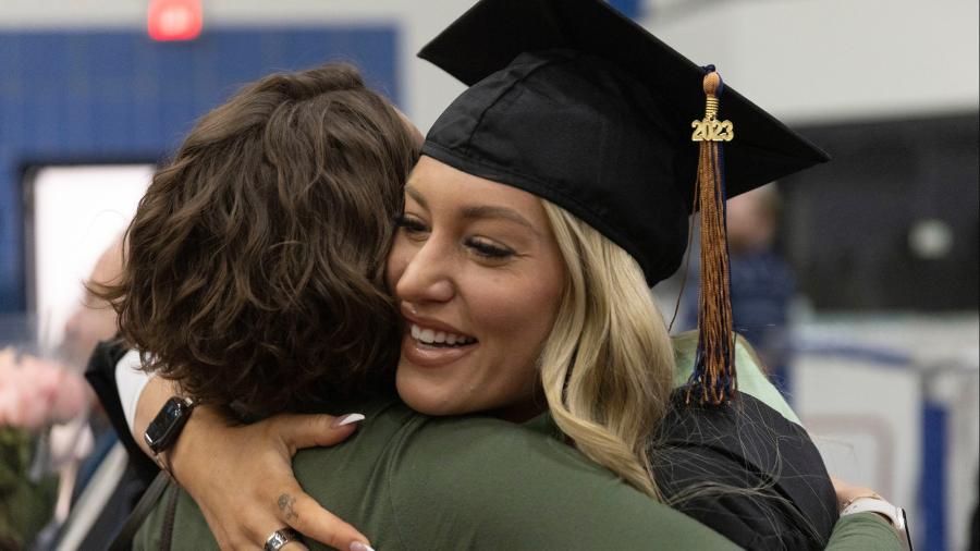 A graduate gets a hug after receiving her diploma.