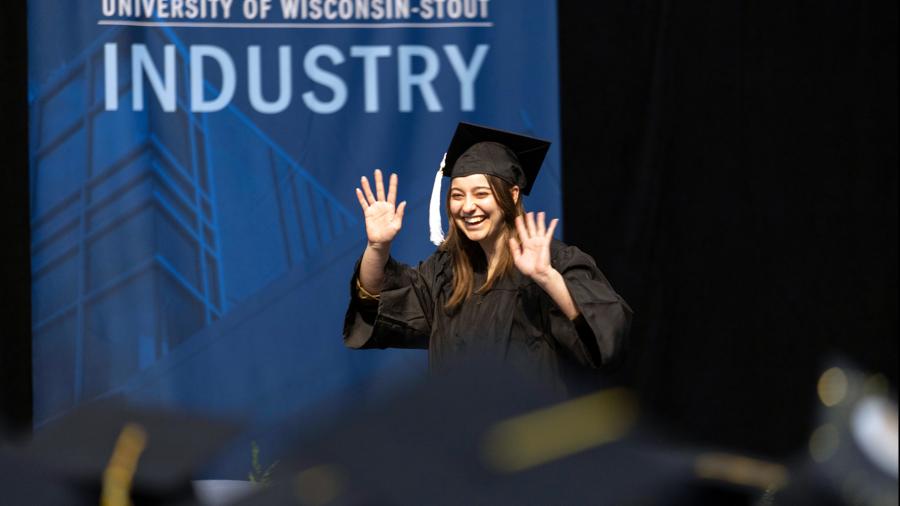 A happy graduate crosses the stage to receive her diploma.