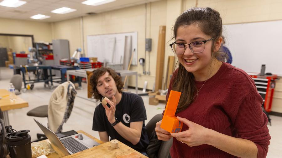 UW-Stout mechanical engineering students Deric McConnell and Grace Goodreid demonstrate a 3D printed prototype part for their wooden toy assembly system industry project in the Senior Design Experience course.
