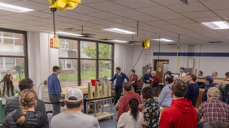 Students, faculty and company representatives watch the tilt table Senior Design Experience demonstration for Viracon in the Fryklund Hall engineering labs.
