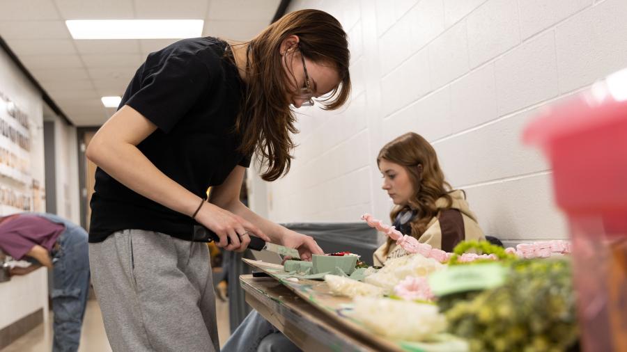 Two students are working at a table in the hallway because there isn't any more in the classroom.