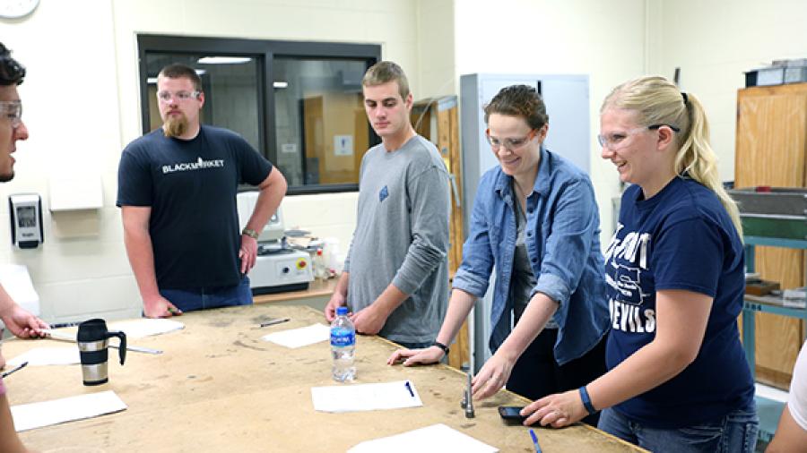 Students engage in collaborative materials testing in engineering lab.