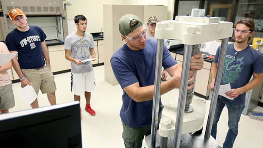 Students perform material testing in lab space.