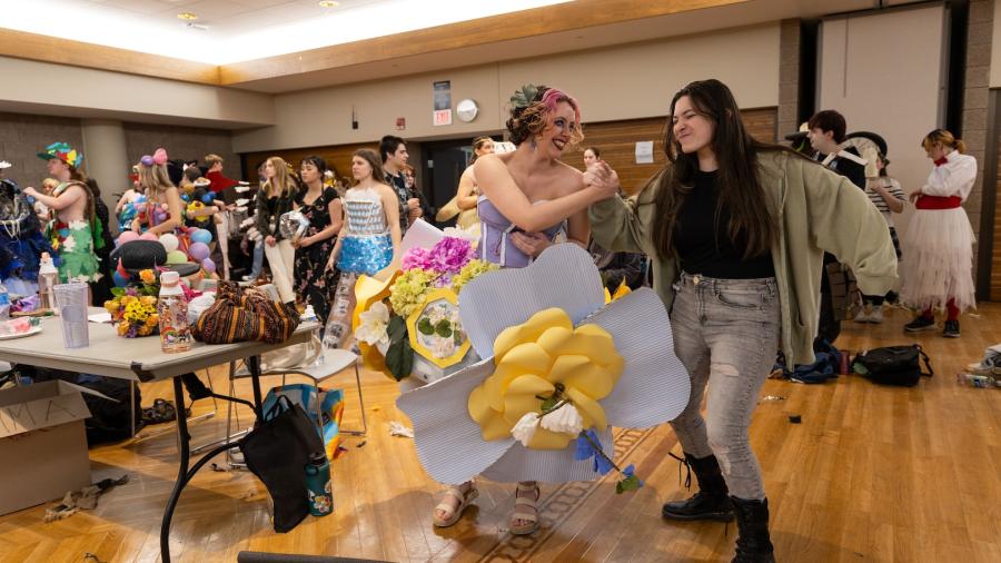 Two student group mates shake hands and smile big after they cross the runway at Fashion Without Fabric.