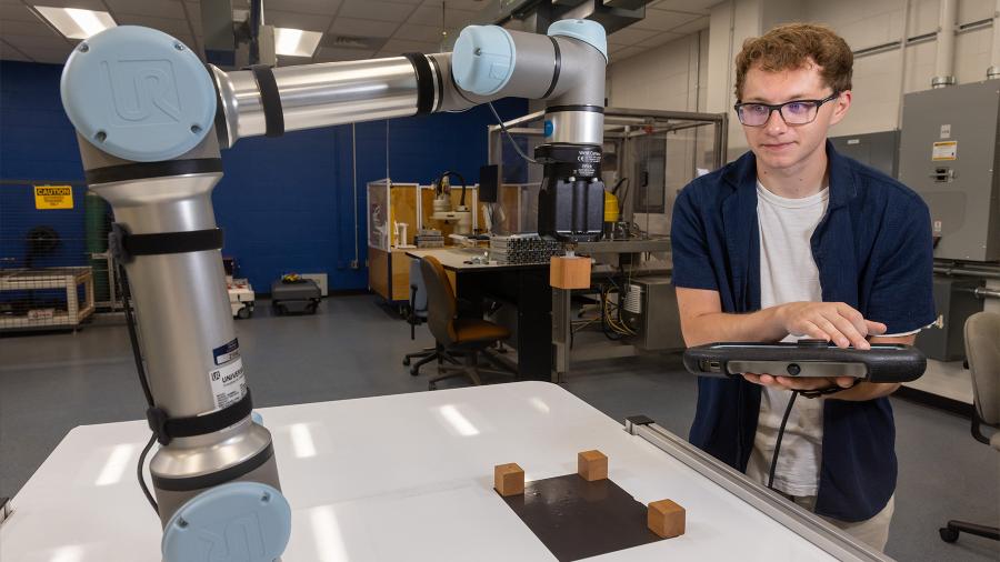 An engineering student uses a Universal Robotic automation machine in the Robotics Lab.