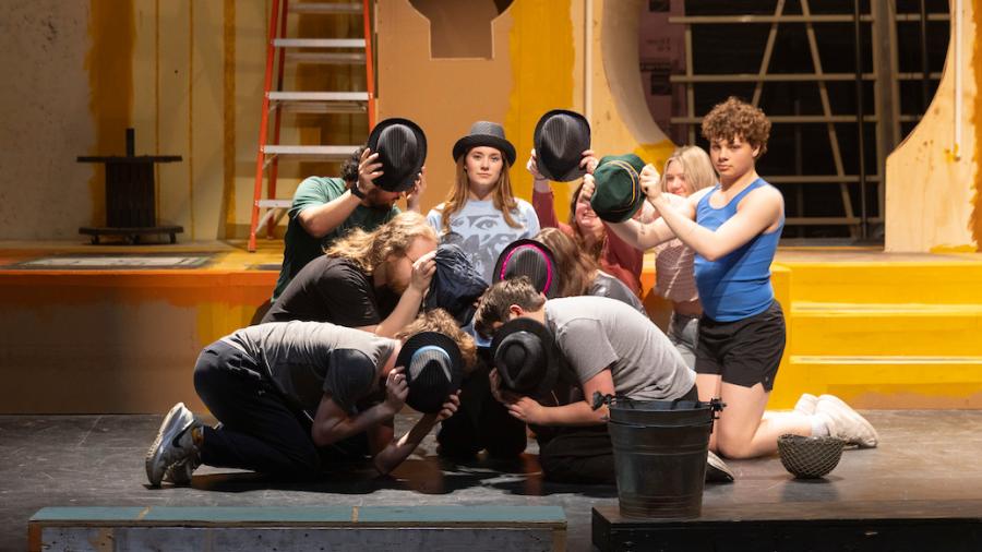Students on stage rehearsing choreography for a theater production
