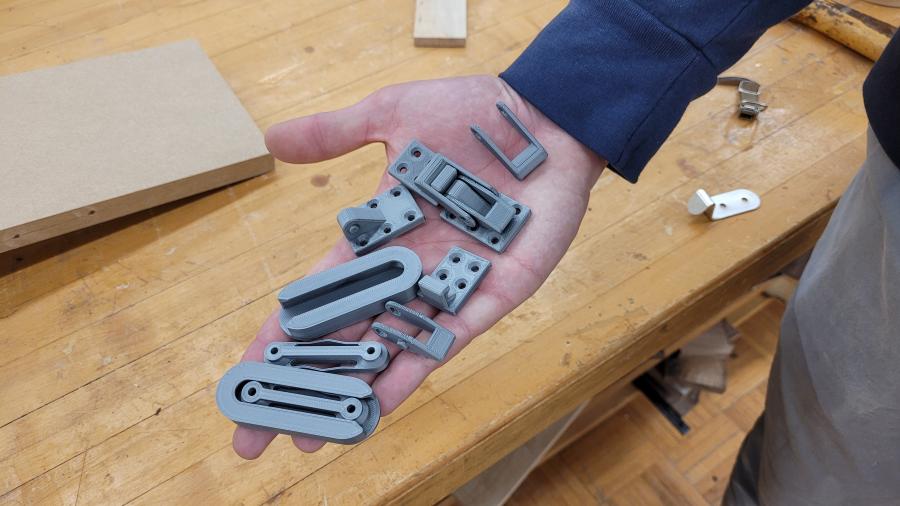 A student holds prototypes of 3D printed fasteners
