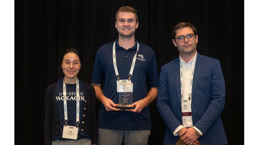 Three people pose with an award plaque