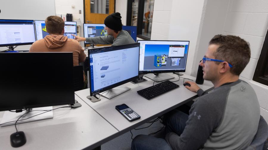 A student sits at a computer, using robotics planning software