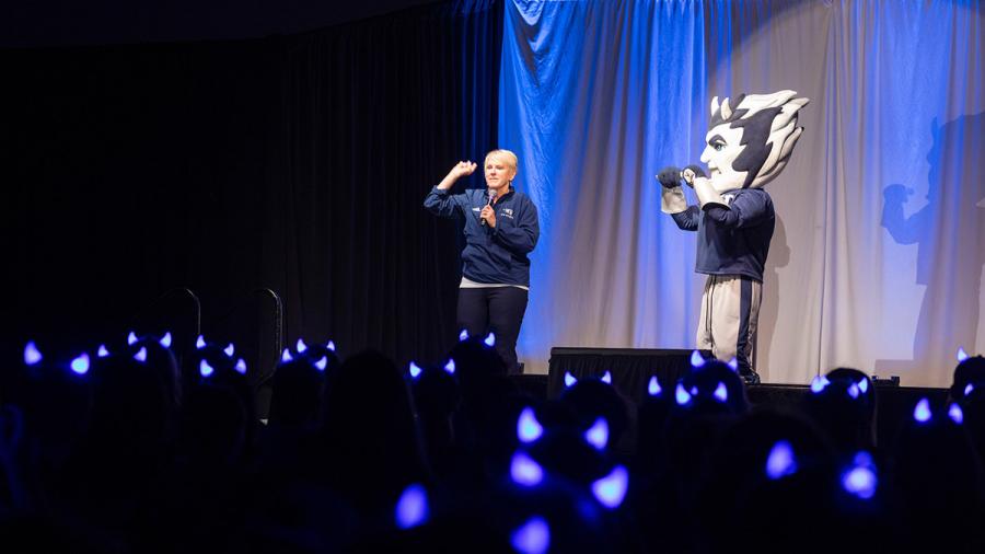A woman and a mascot on stage