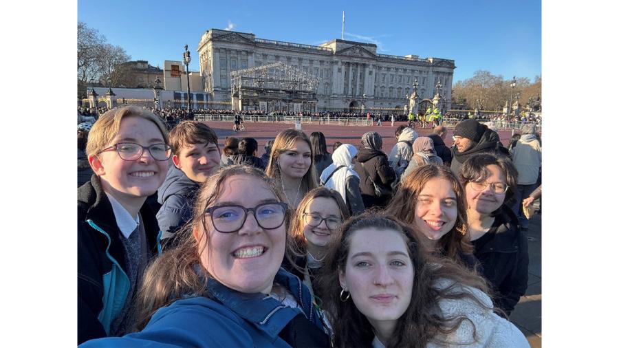 A group of students poses for a photo outside of Buckingham Palace during the changing of the guards