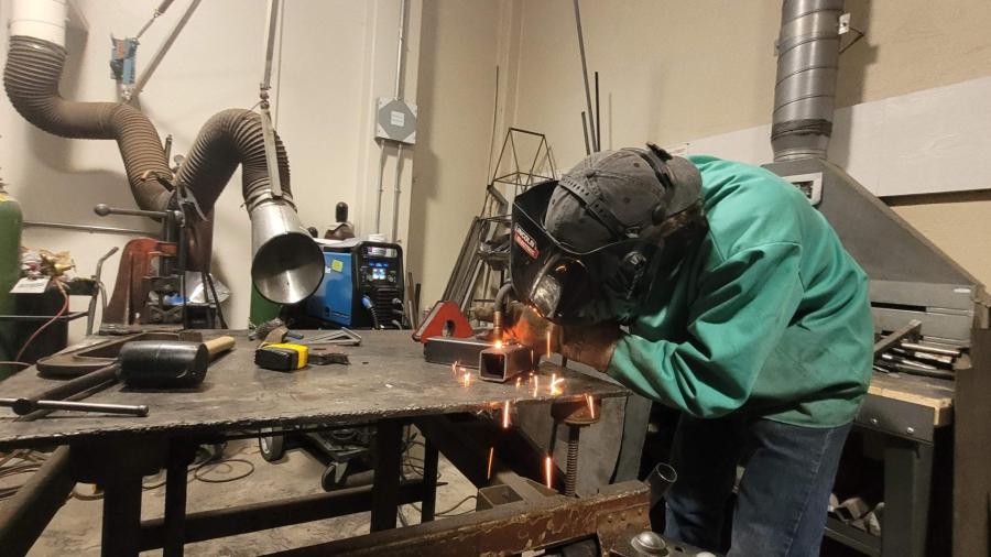 An industrial design student welding a T-bar.