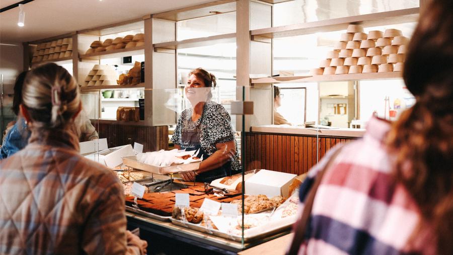 Staff at a bakeshop prepare croissants for a line of customers