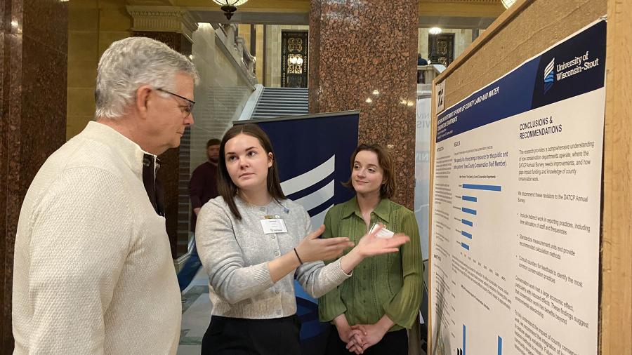 Three people looking at research poster