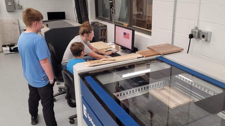 STEAM Construction campers and instructor preparing to use the laser engraver