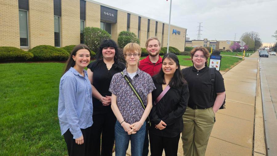 A group of students stands outside of a printing company.