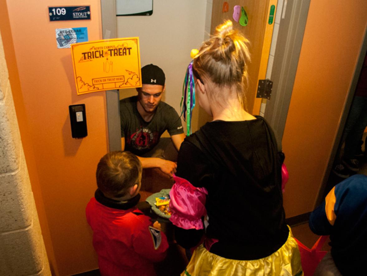 A UW-Stout student hands out candy to children at Red Cedar Hall during the 2016 trick-or-treat event on north campus.