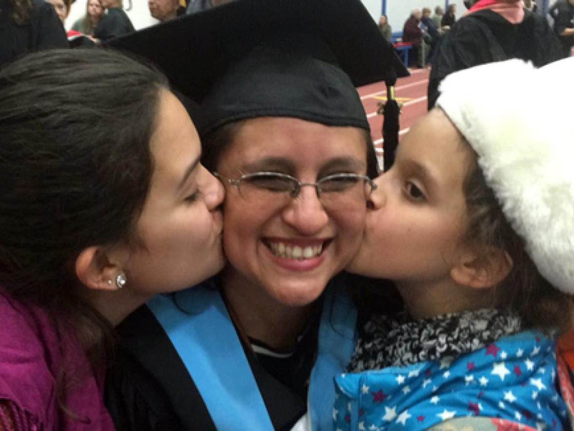 Online student Veronica Solano receives a congratulatory kiss after commencement from daughters, Nasim, left, and Anisa.