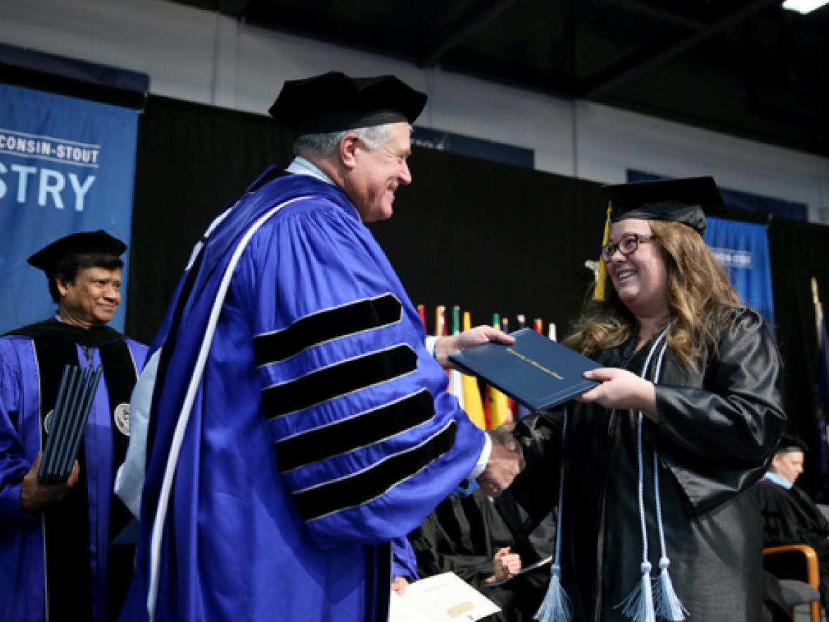 Chancellor Bob Meyer congratulates graduate Grace Sutula as she crosses the stage at commencement Saturday, Dec. 16, in Johnson Fieldhouse. Sutula earned a degree in applied mathematics and computer science.