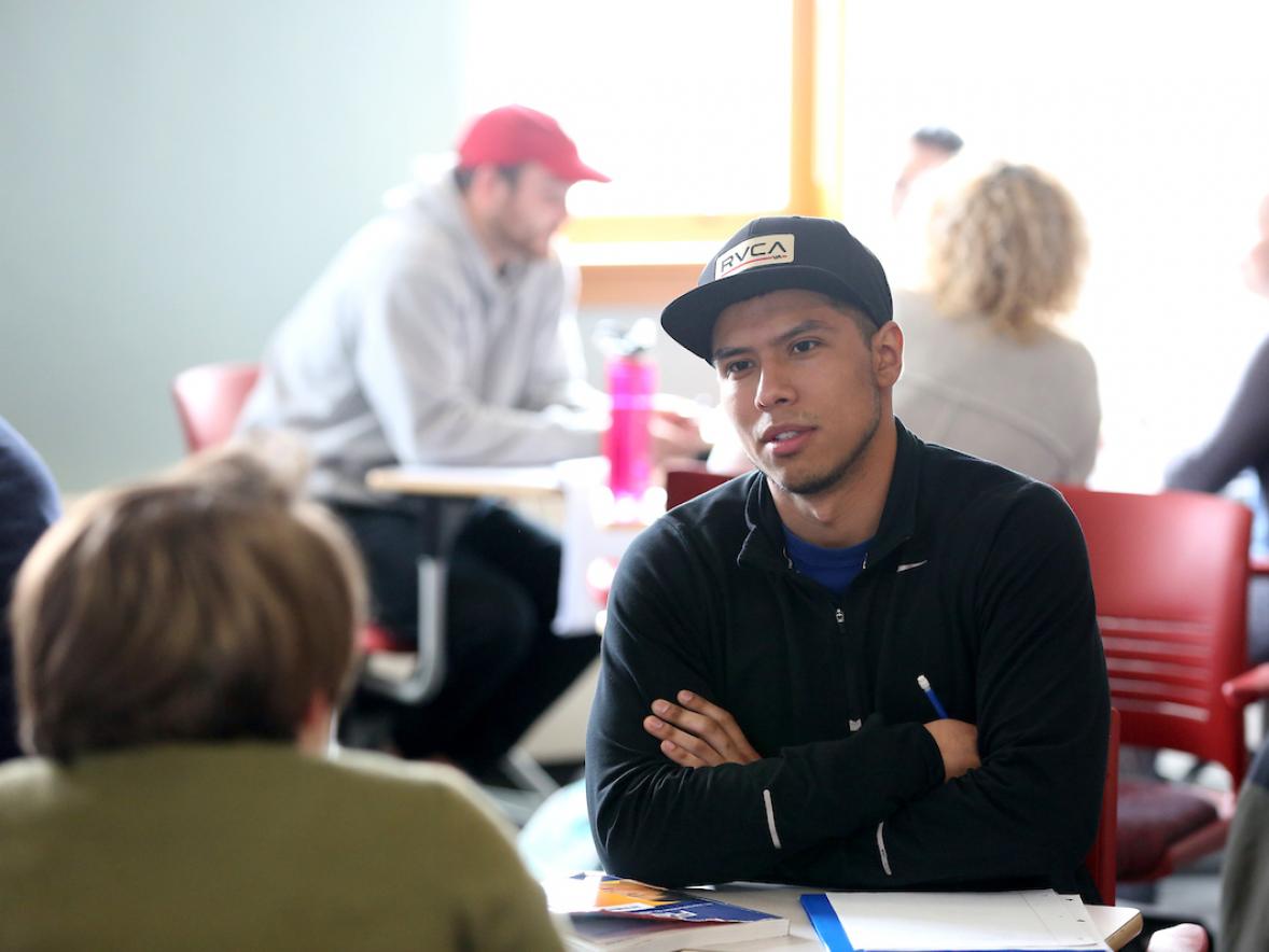 Male student talking in a small group discussion in class.