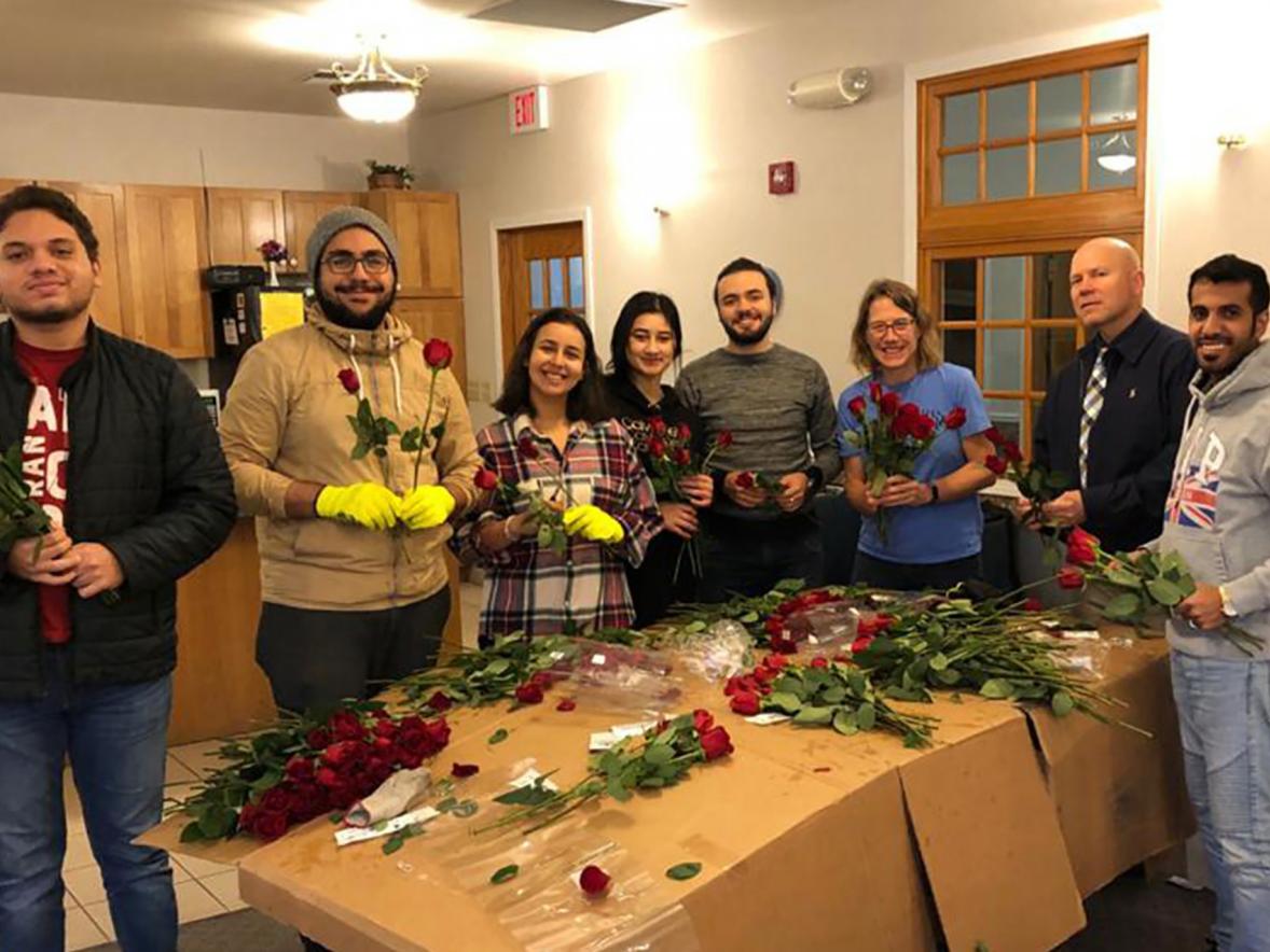 International students at UW-Stout can qualify for a scholarship, which includes community service. Helping the Rotary Club of Menomonie deliver roses to raise money for service projects are Fedi Soltani, second from left; Nilu Omarova, fourth from left; and Sulaiman Alharbi, right. 