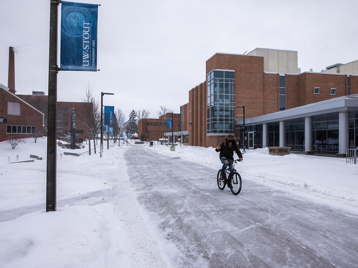 A bicyclist rides across campus in freshly fallen snow. / UW-Stout photo