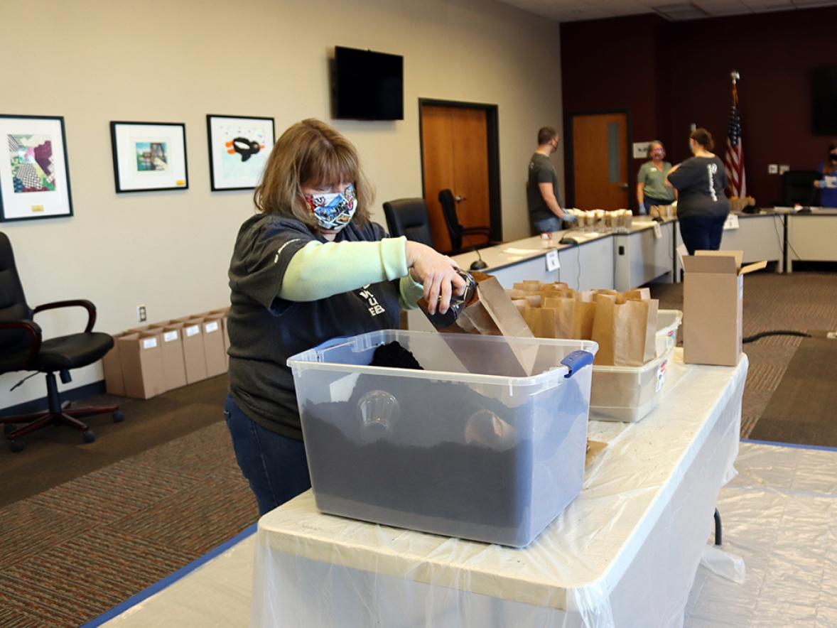 Xcel Energy employee Pam Taylor pours potting soil into brown bags for the kits.