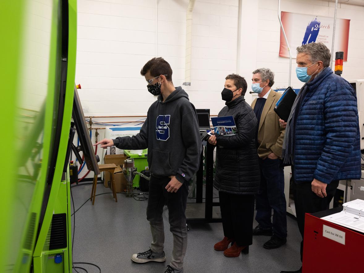 UW-Stout plastics engineering major Jared Pavlis demonstrates for Missy Hughes, WEDC secretary and CEO, how to make an injection molded part for a catheter. Looking on are Menomonie Mayor Randy Knaack, third from left, and Randy Hulke, executive director of UW-Stout’s Discovery Center.
