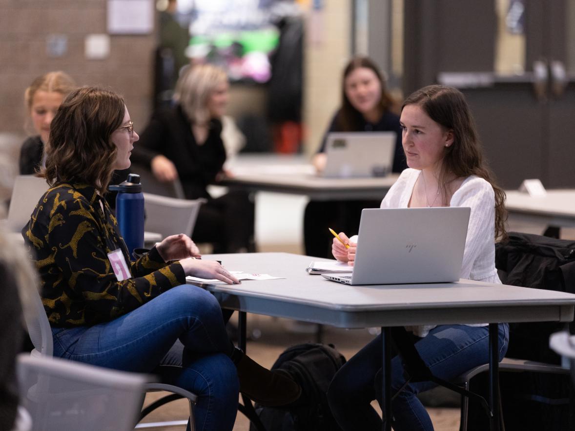 Two students sitting at a table with a laptop
