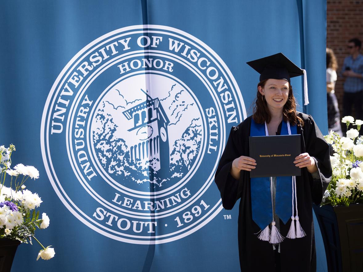 A student proudly displays her diploma during the spring 2022 commencement at UW-Stout.