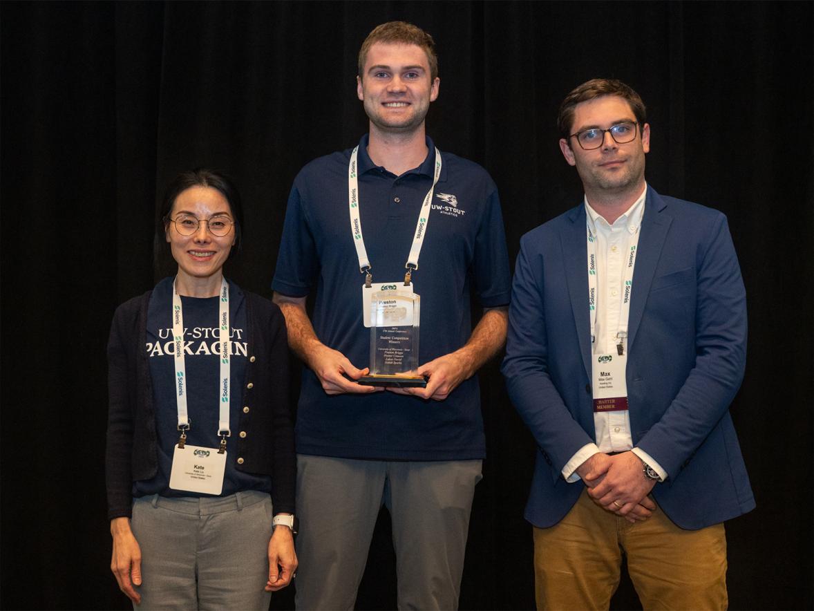 Three people pose with an award plaque