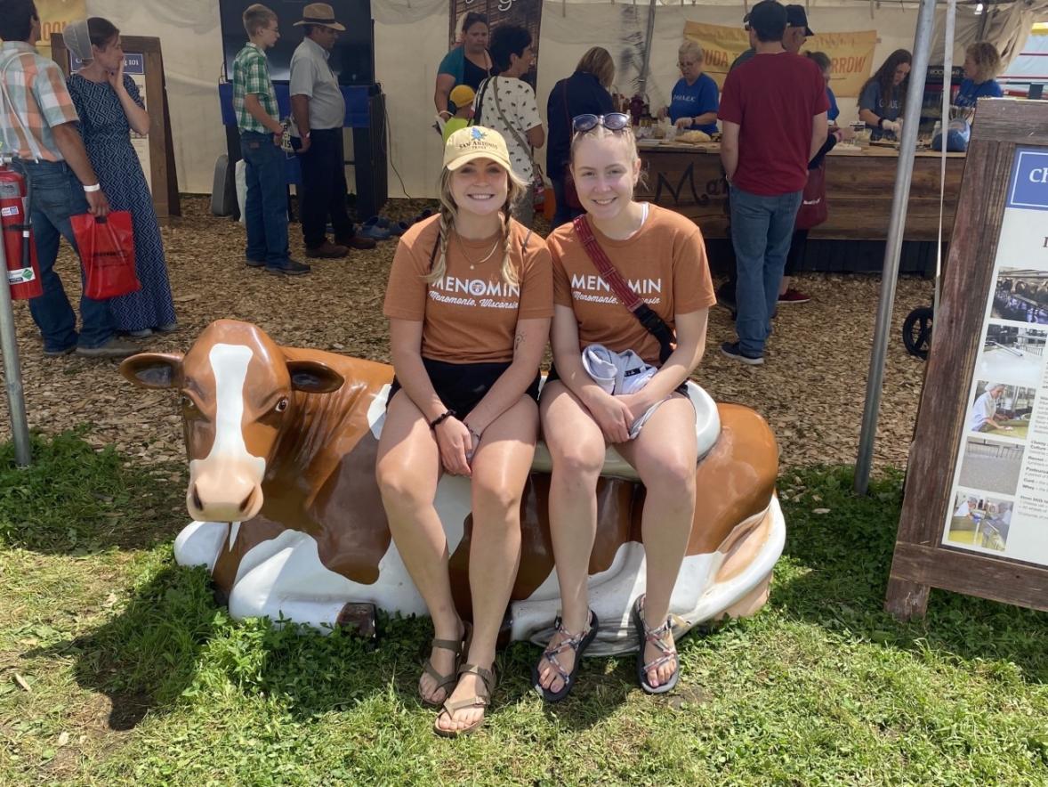 Two undergraduate students sitting on a cow statue.