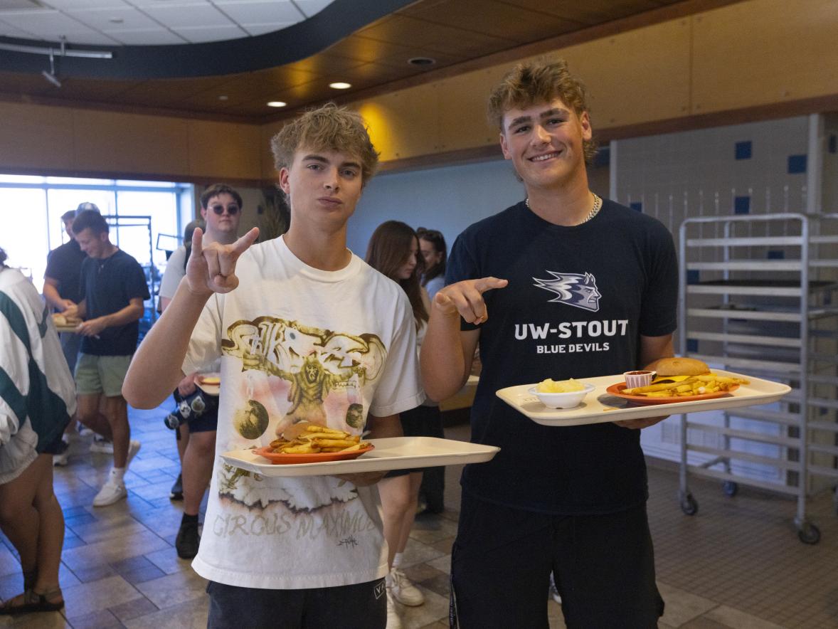 Students smiling while holding food from the cafeteria.