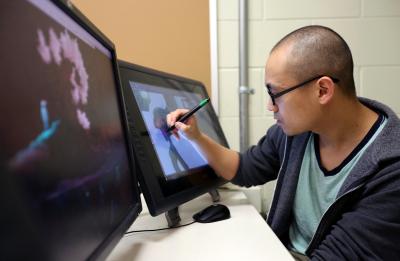 UW-Stout graduate Hue Vang working on the game Sun of the Children that took second place at the Intel University Game Showcase and Expo in San Francisco. UW-Stout photo by Brett T. Roseman
