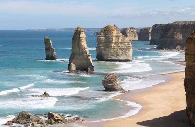 The Australian coastline with tall rock formations and rolling blue waves.