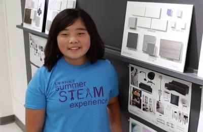 A student displaying their interior design project at the Summer STEAM Camp showcase.