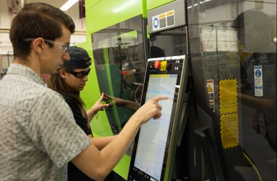 Guys programming a machine in a lab on campus